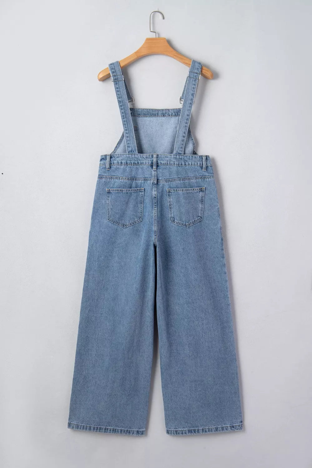 Retro pleated wide-leg denim jumpsuit with buttoned straps and back pockets.