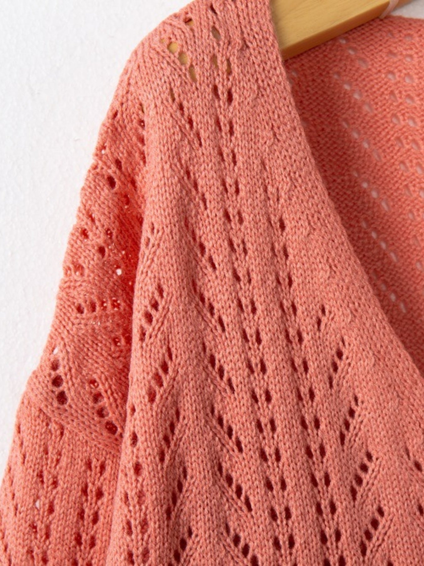 Burnt Coral knit cardigan with openwork diamond pattern and textured sleeves.