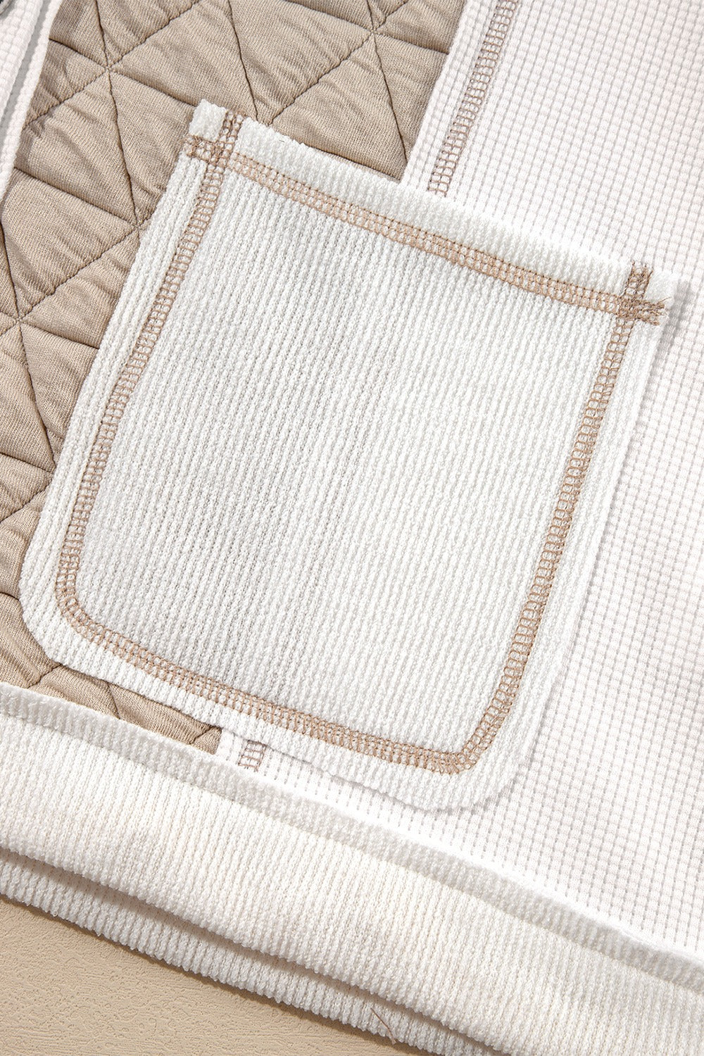 White waffle knit hoodie with quilted panel detail and contrast stitching on pocket.