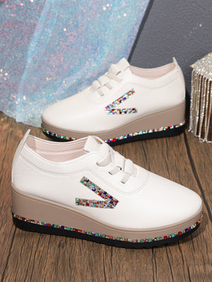 White wedge sneakers with colorful rhinestone embellishments on the side and sole.