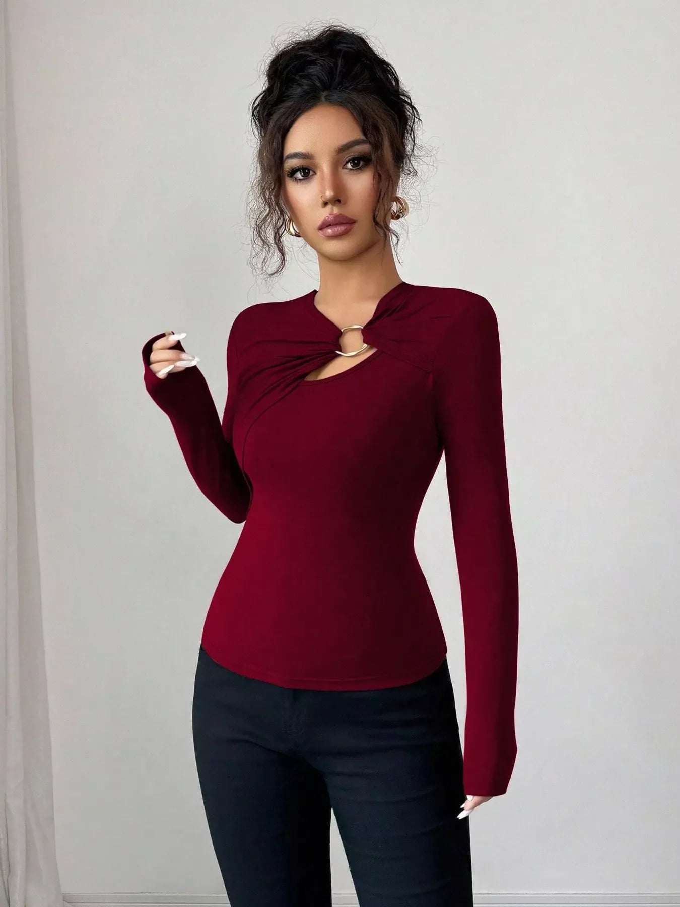 Burgundy long-sleeve tee with asymmetrical cutout and gold ring detail at neckline