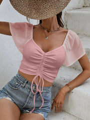 Pink ribbed crop top with sweetheart neckline, adjustable drawstring, and sheer chiffon flutter sleeves.