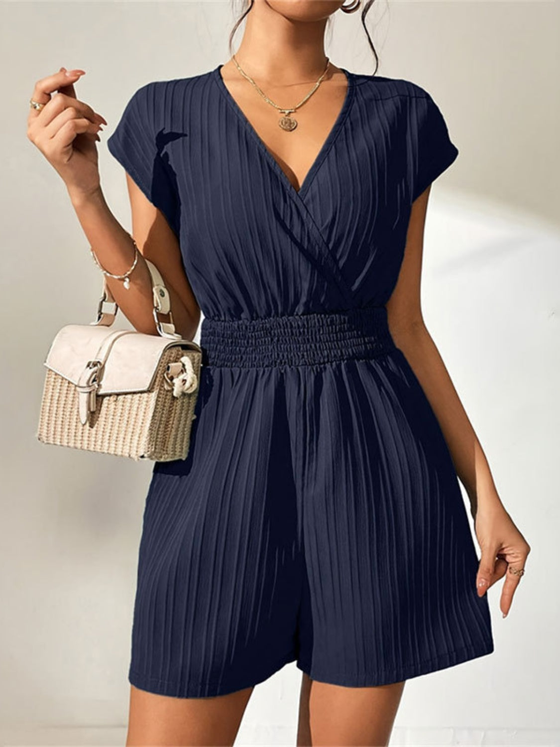 Navy textured wrap romper with smocked waist and short sleeves.