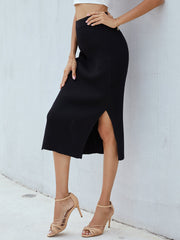 Black ribbed knit midi skirt with a side slit, styled with strappy heels.