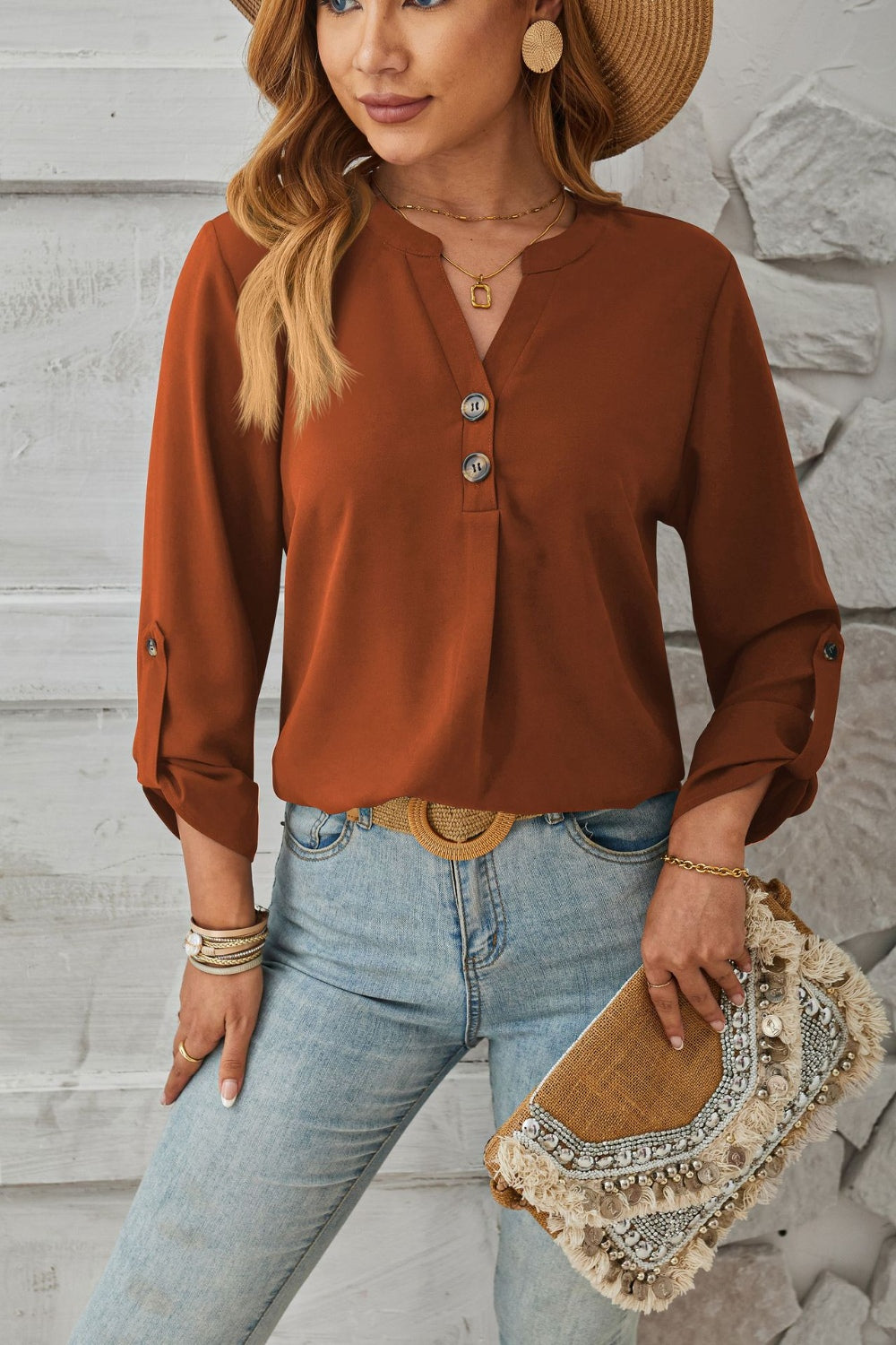 Rust V-neck button-down blouse with cuffed sleeves and roll-tab detail.