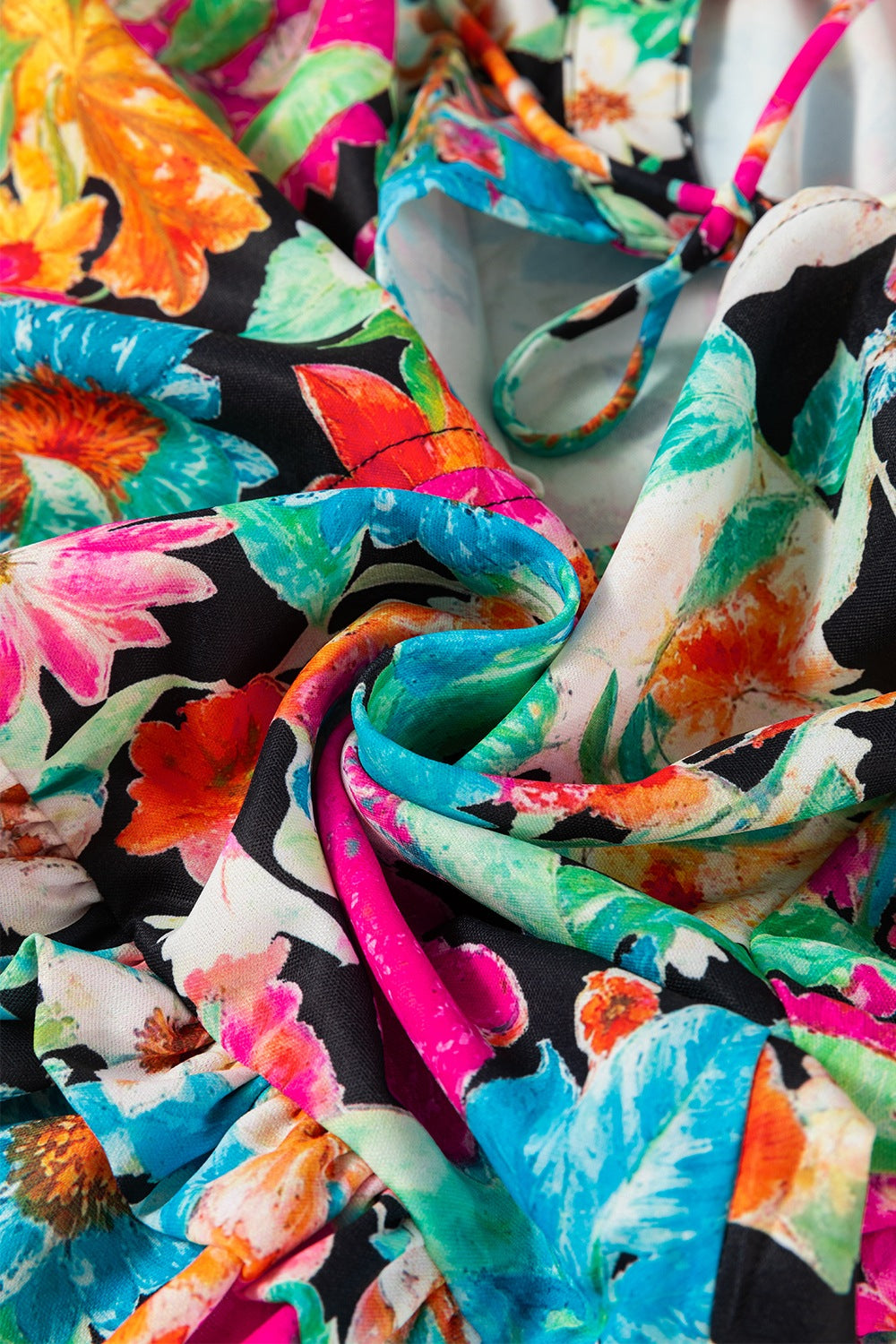 Vibrant floral print blouse with tie straps and tassel trim detail.