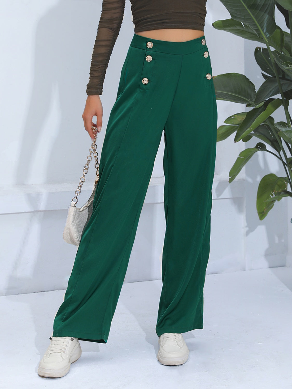 Dark green wide-leg trousers with gold button detail and a high waist.