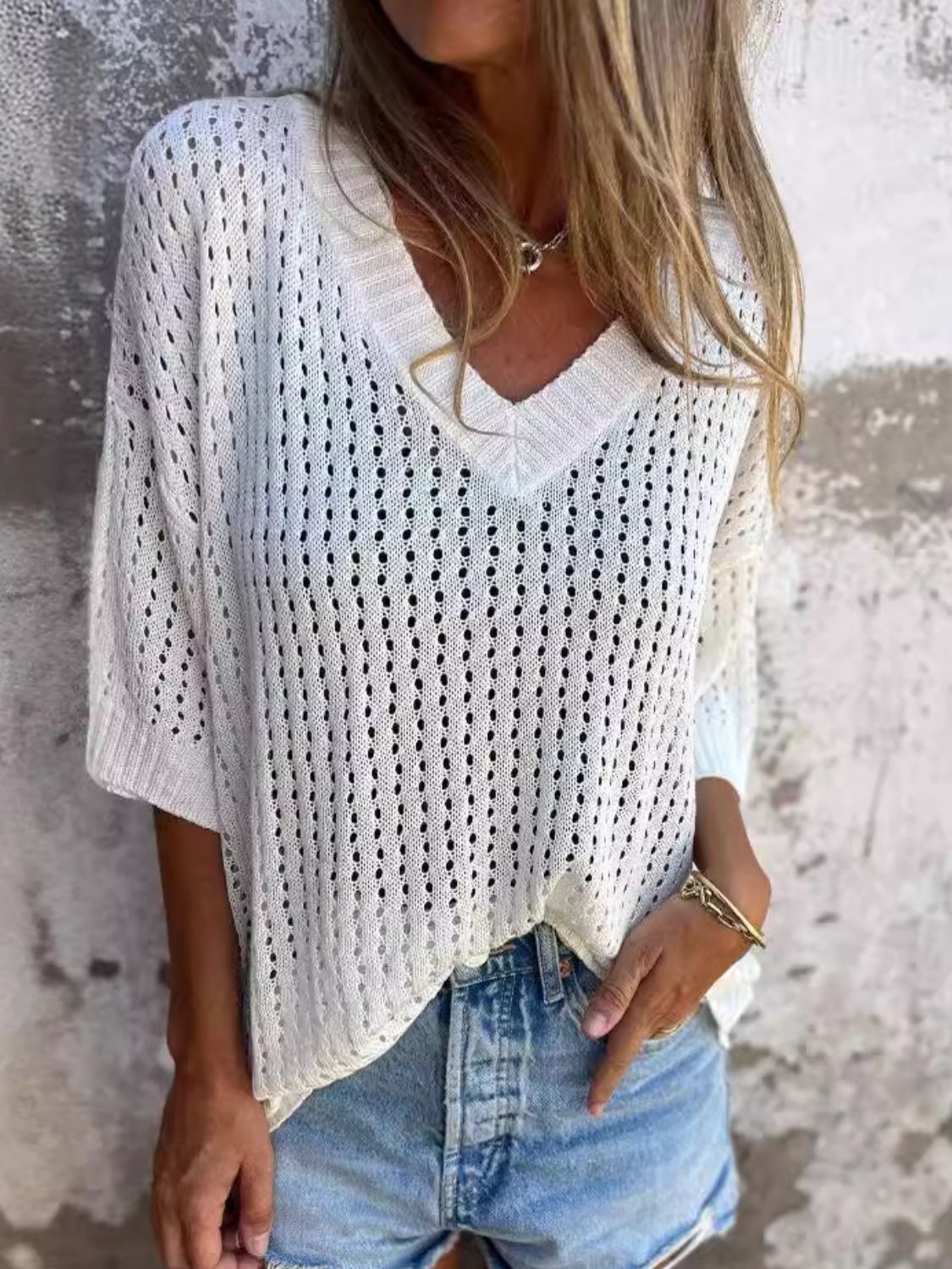 White open-knit V-neck sweater with relaxed fit and short sleeves, styled with denim shorts.