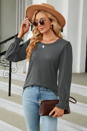Dark gray long sleeve blouse with smocked cuffs and puff sleeves.
