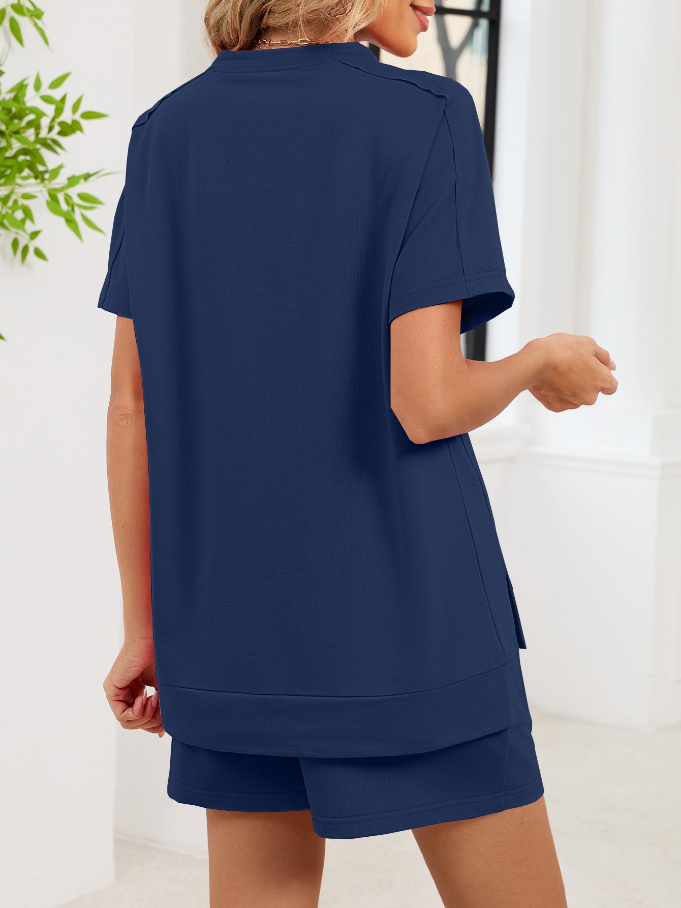 Navy blue relaxed two-piece set with short sleeves and pockets, featuring a high-low hem.