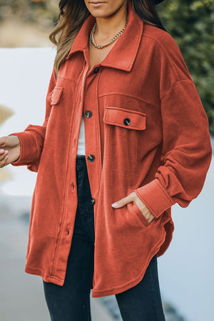 Fleece shirt jacket in orange with patch pockets and button front.