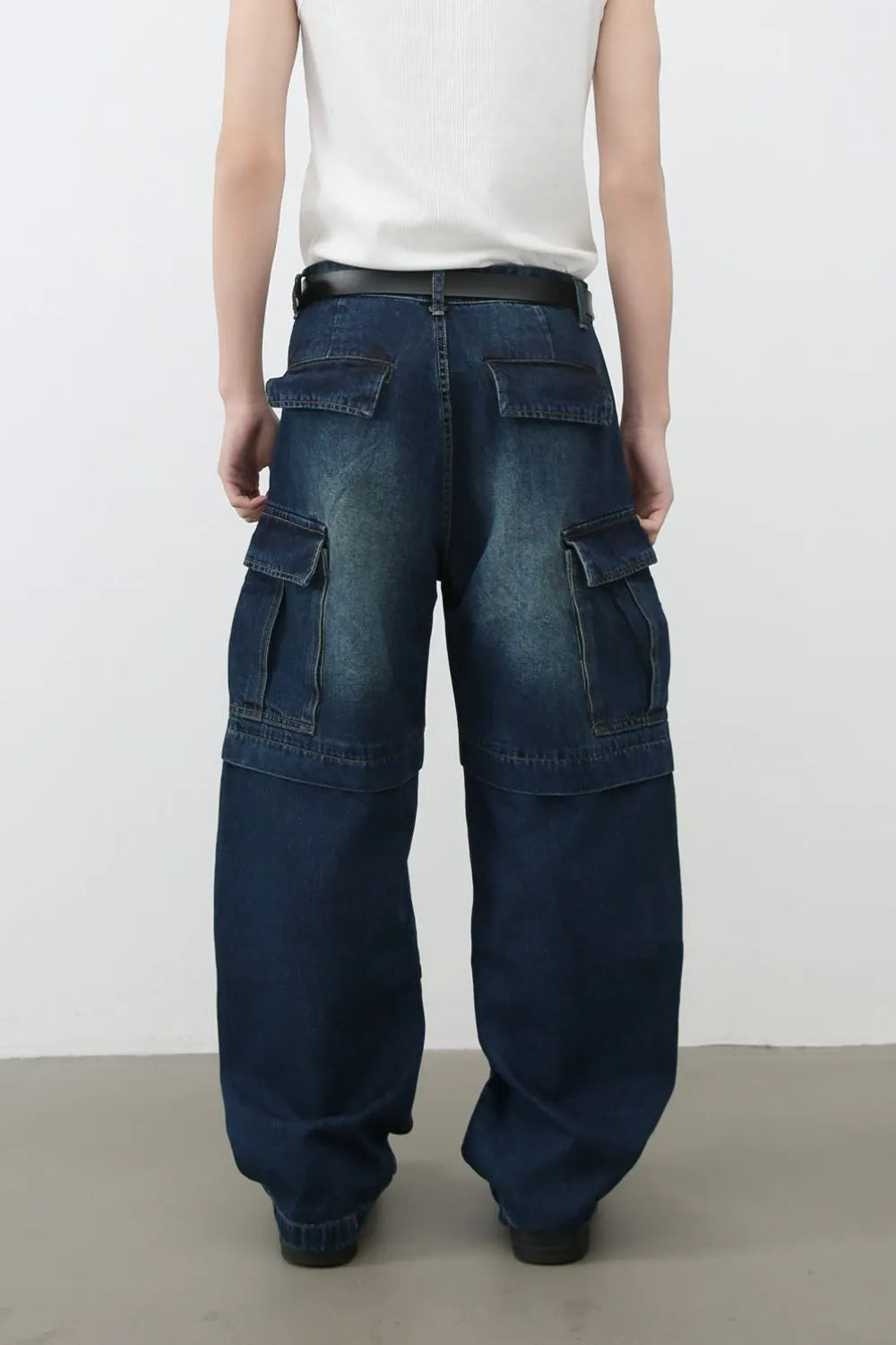 Dark denim cargo pants with layered pockets and a relaxed fit.
