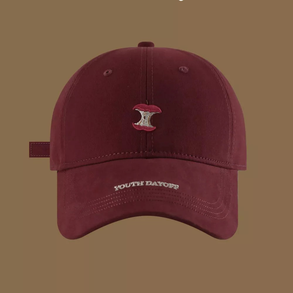 Red baseball cap with embroidered apple core and "YOUTH DAYOFF" text.