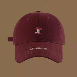 Red baseball cap with embroidered apple core and "YOUTH DAYOFF" text.