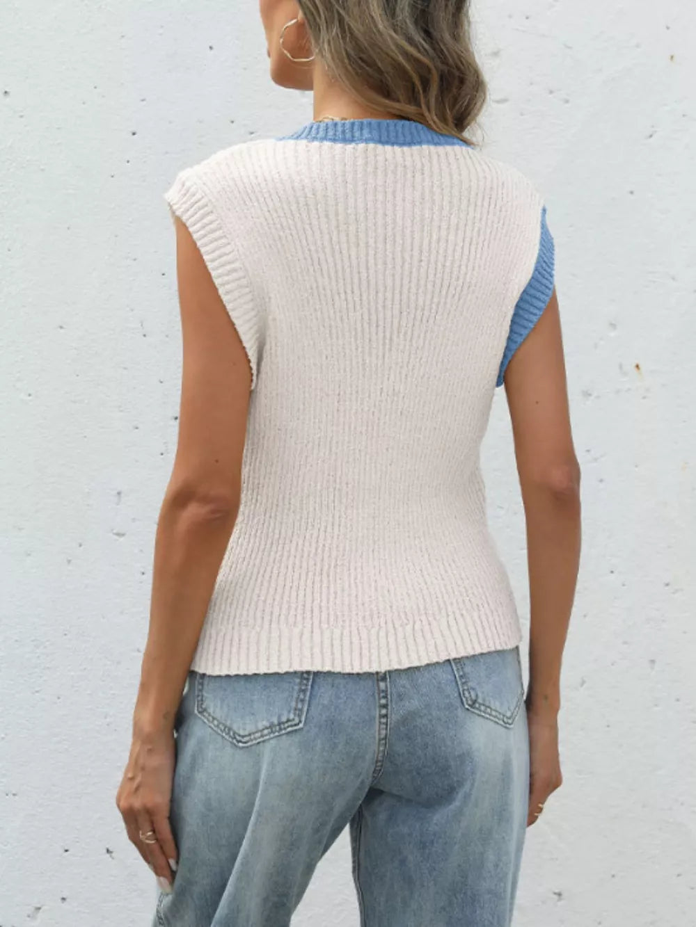 Sleeveless knit cardigan in cream with blue trim and ribbed texture.