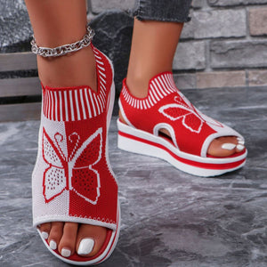 Red and white knit open-toe wedge sandals with butterfly motif and mesh detail.