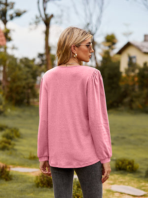 Pink ruffled henley sleeve blouse with gathered shoulder detail.