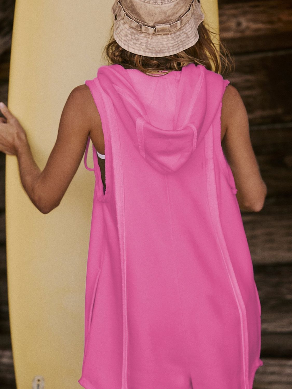 Sleeveless hooded romper in hot pink with raw edges and a pocket detail.