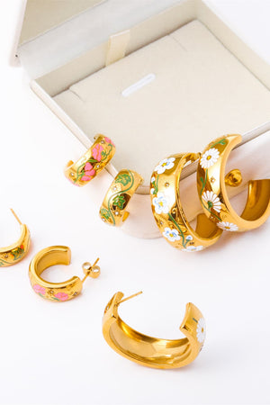 Gold hoop earrings with floral enamel details in pink, green, and white daisy designs.