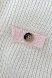 Cream knit cardigan with pink trim detail and button closure.