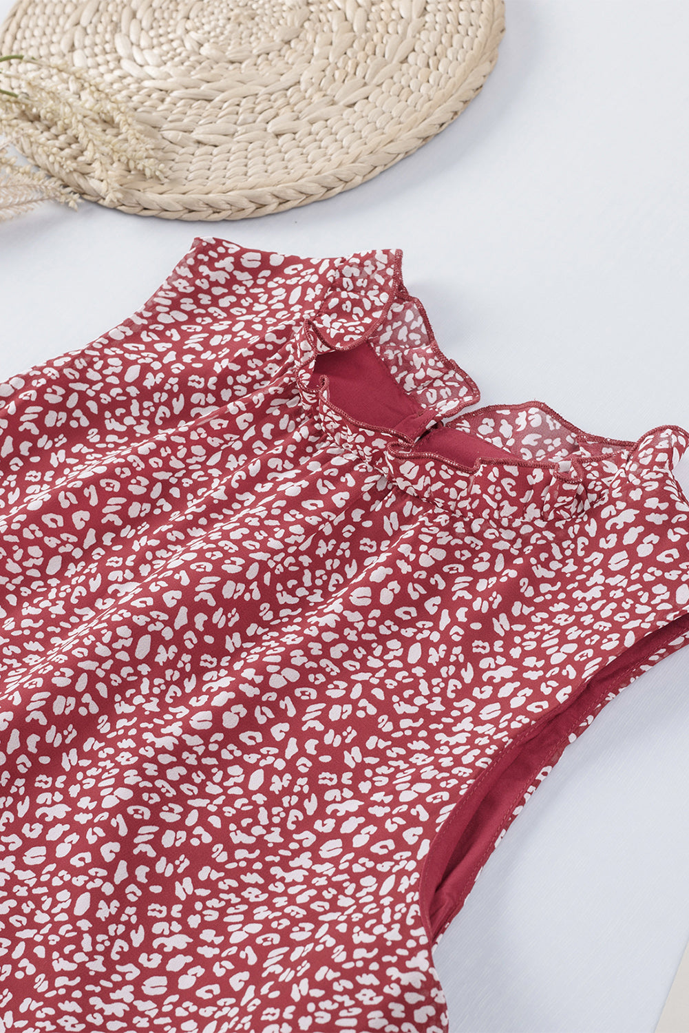 Burgundy printed sleeveless blouse with ruffled neckline detail.