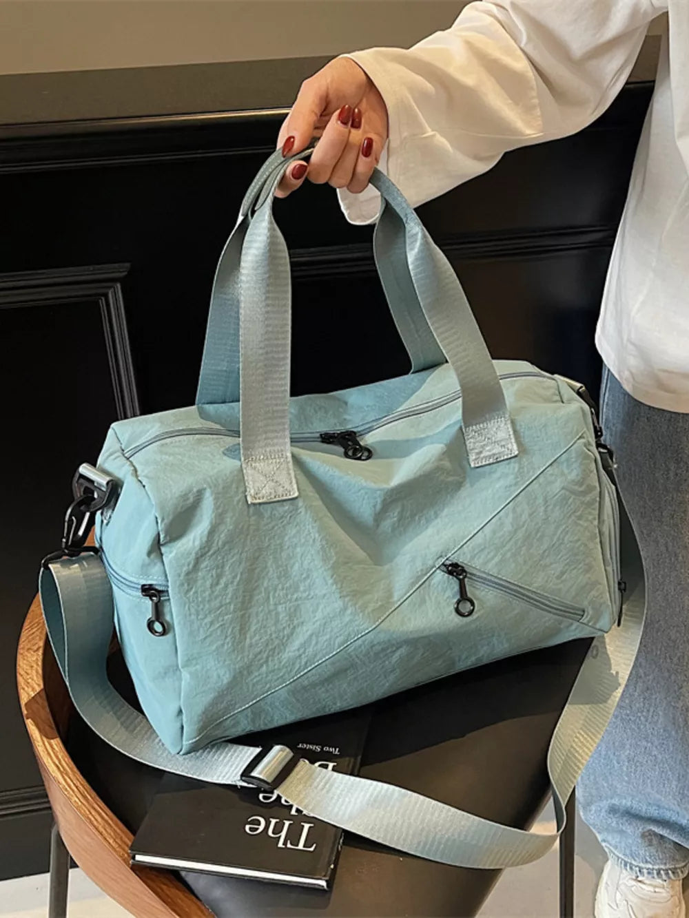 Light blue nylon duffel bag with multiple zippered pockets and adjustable shoulder strap.