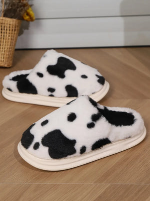 Cow print faux fur house slides in black and white with a cream sole.