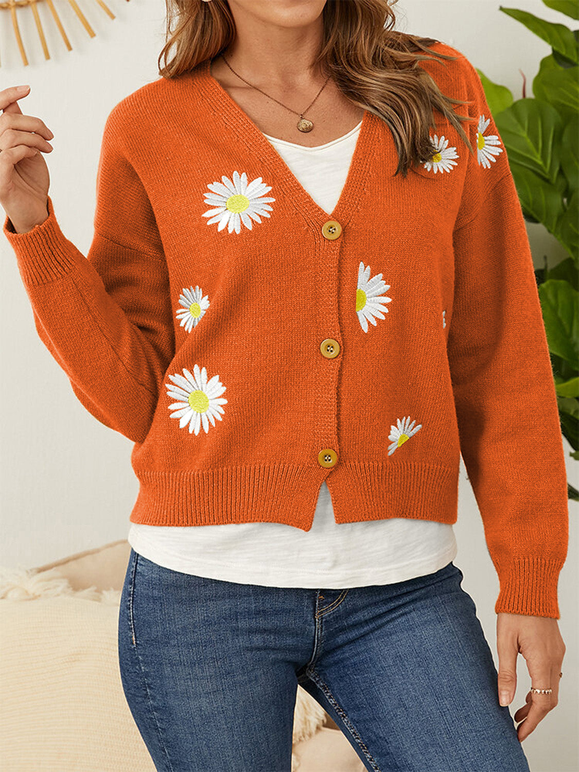 Orange V-neck cardigan with daisy embroidery and button front.