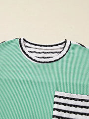 Turquoise twisted ribbed long-sleeve top with striped neckline and pocket detail.