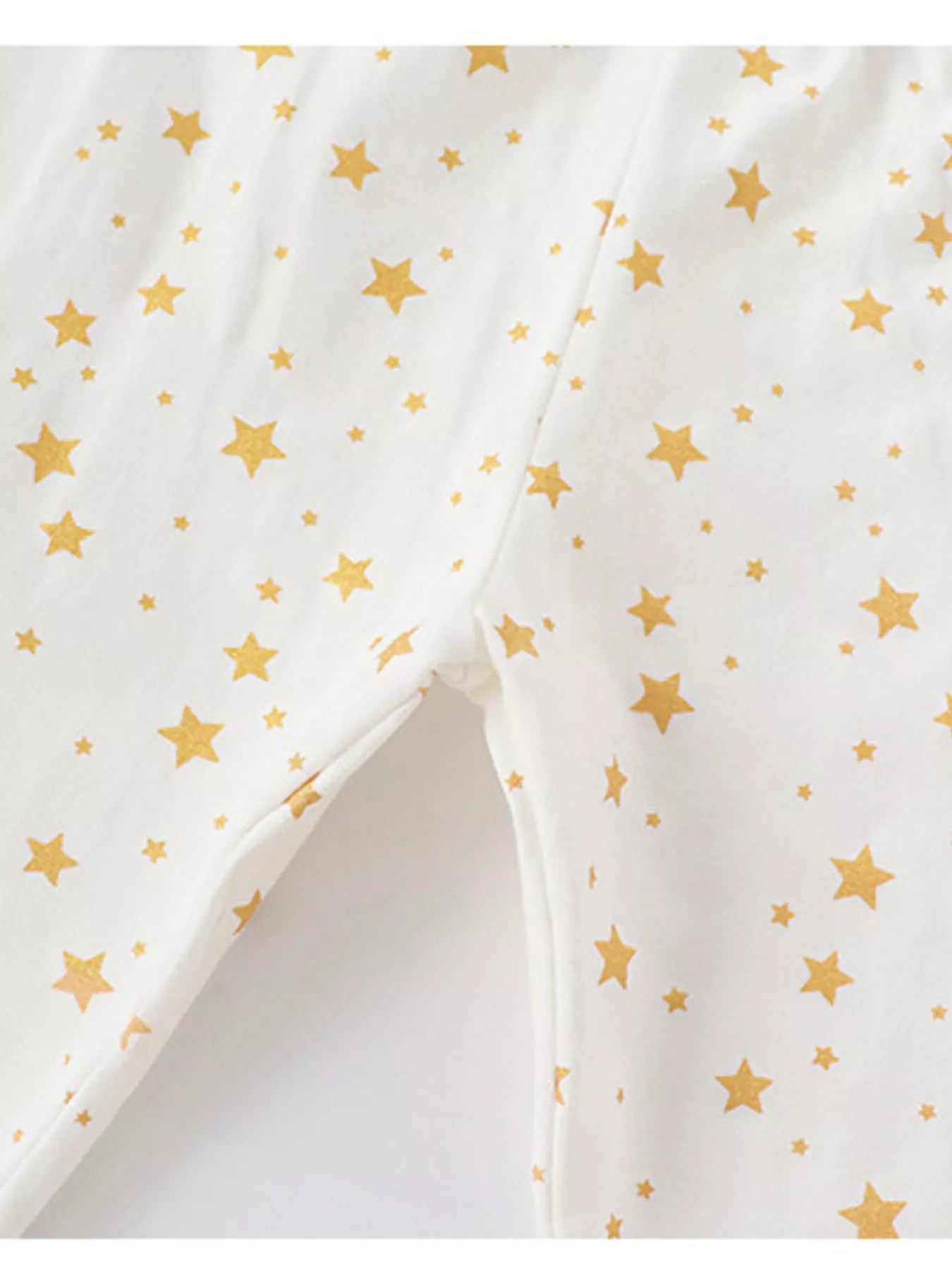 Kids' cotton pajamas in blush pink with a gold star print, showing inseam detail.