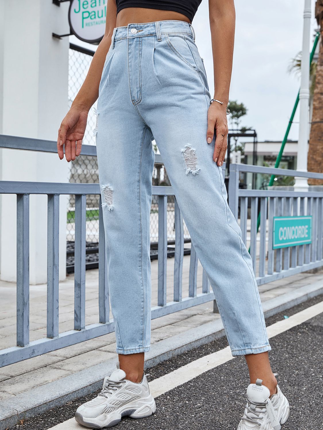 Light wash denim jeans with high-rise, pleats, and distressed details.