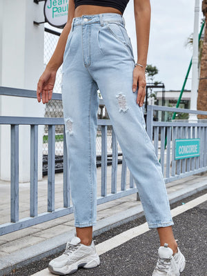 Light wash denim jeans with high-rise, pleats, and distressed details.