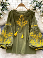 Green embroidered tie-neck blouse with yellow wheat detail and tassels.