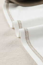 Colorblock knit top in white with tan contrast stitching detail.