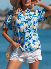 Vibrant floral print cotton blouse with puff sleeves and V-neck, styled with white shorts.