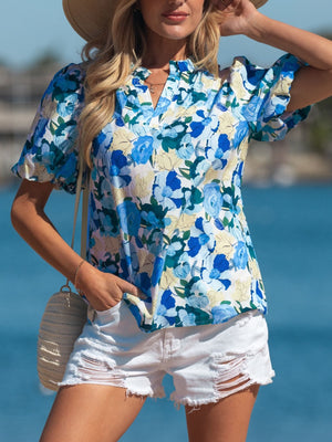Vibrant floral print cotton blouse with puff sleeves and V-neck, styled with white shorts.