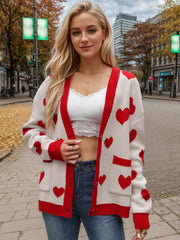 Cream acrylic cardigan with red heart intarsia pattern, button front, and pockets.