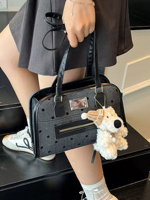 Sophisticated black polka dot shoulder bag with a zippered pocket and a plush dog charm.