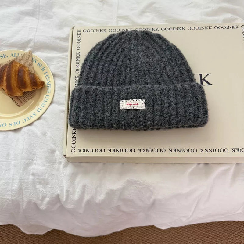 Dark Gray chunky knit beanie with ribbed texture and a small white label with red text.