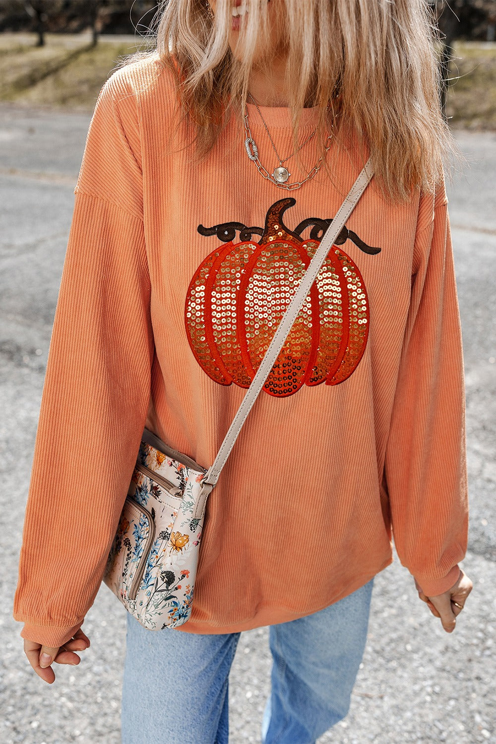 Orange corduroy sweatshirt with sequin pumpkin graphic, relaxed fit, crew neck.