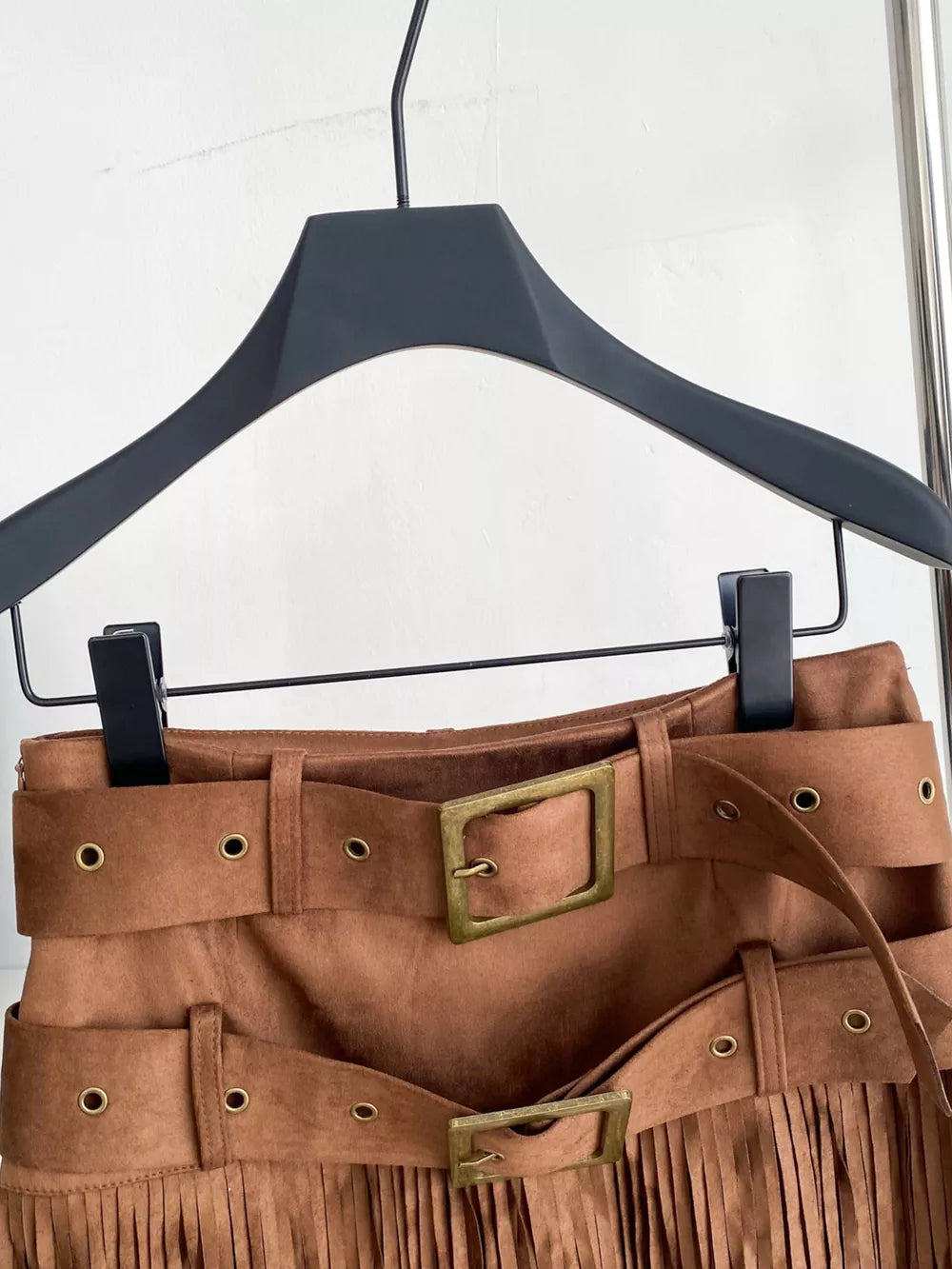 Belted mini skirt in brown suede with fringe and antique brass buckles.