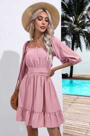 Blush pink mini dress with square neck, tie waist, ruffled hem, and puff sleeves.
