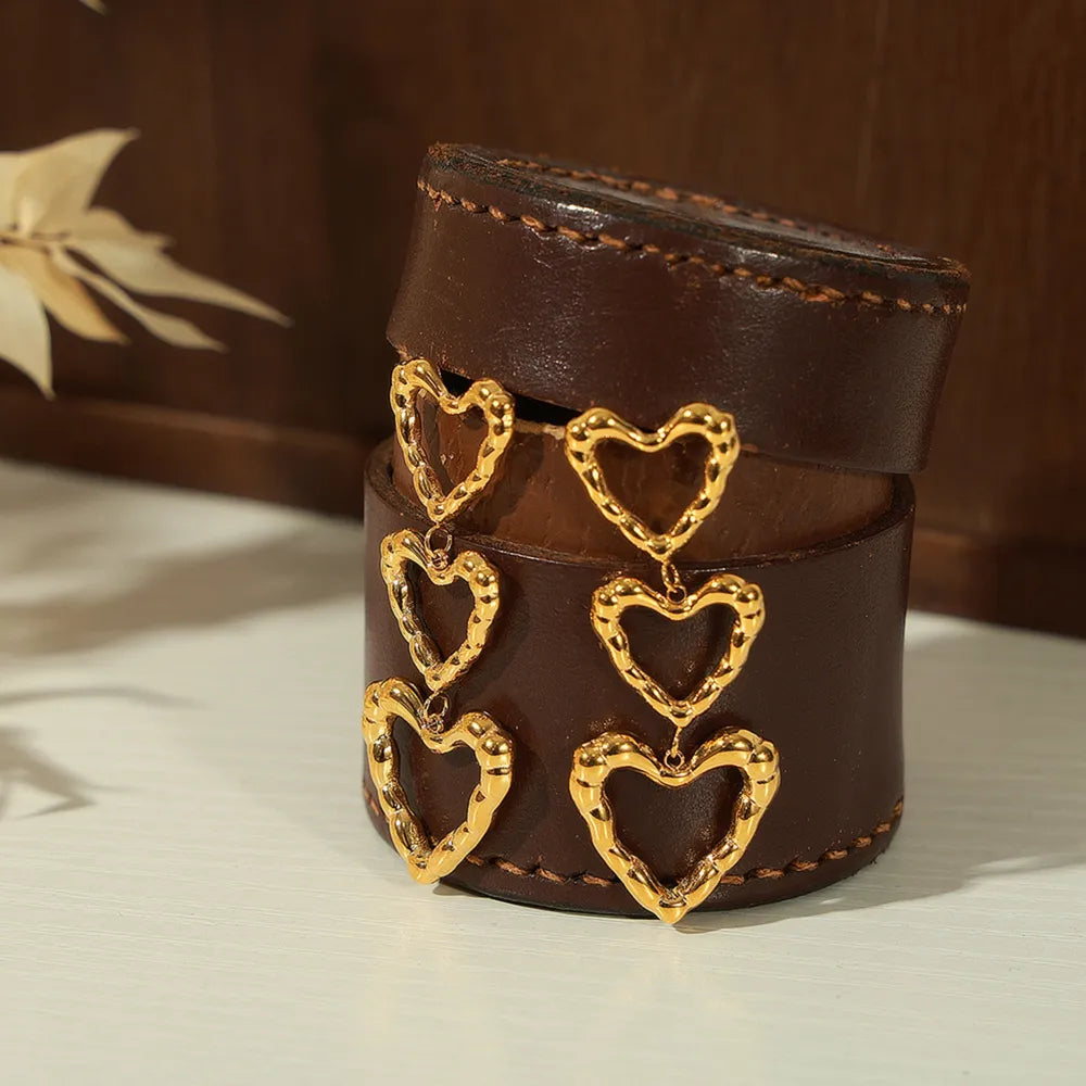 Gold triple heart drop earrings with textured detail.