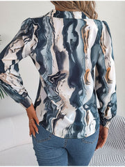 Women's abstract swirl print silk blouse with puff sleeves and button detail.