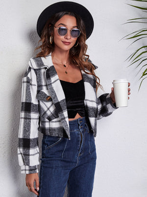Chic plaid jacket in black and white with buttoned pockets and collar, worn open over a black top.