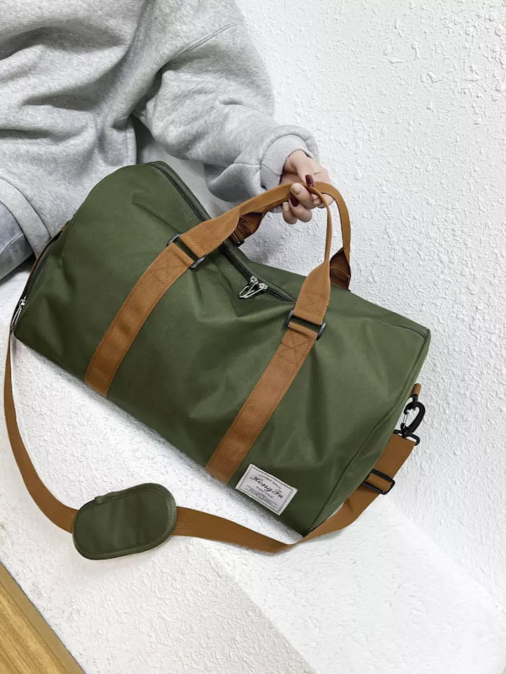 Green Oxford cloth duffel bag with brown straps and shoulder strap, perfect for travel.