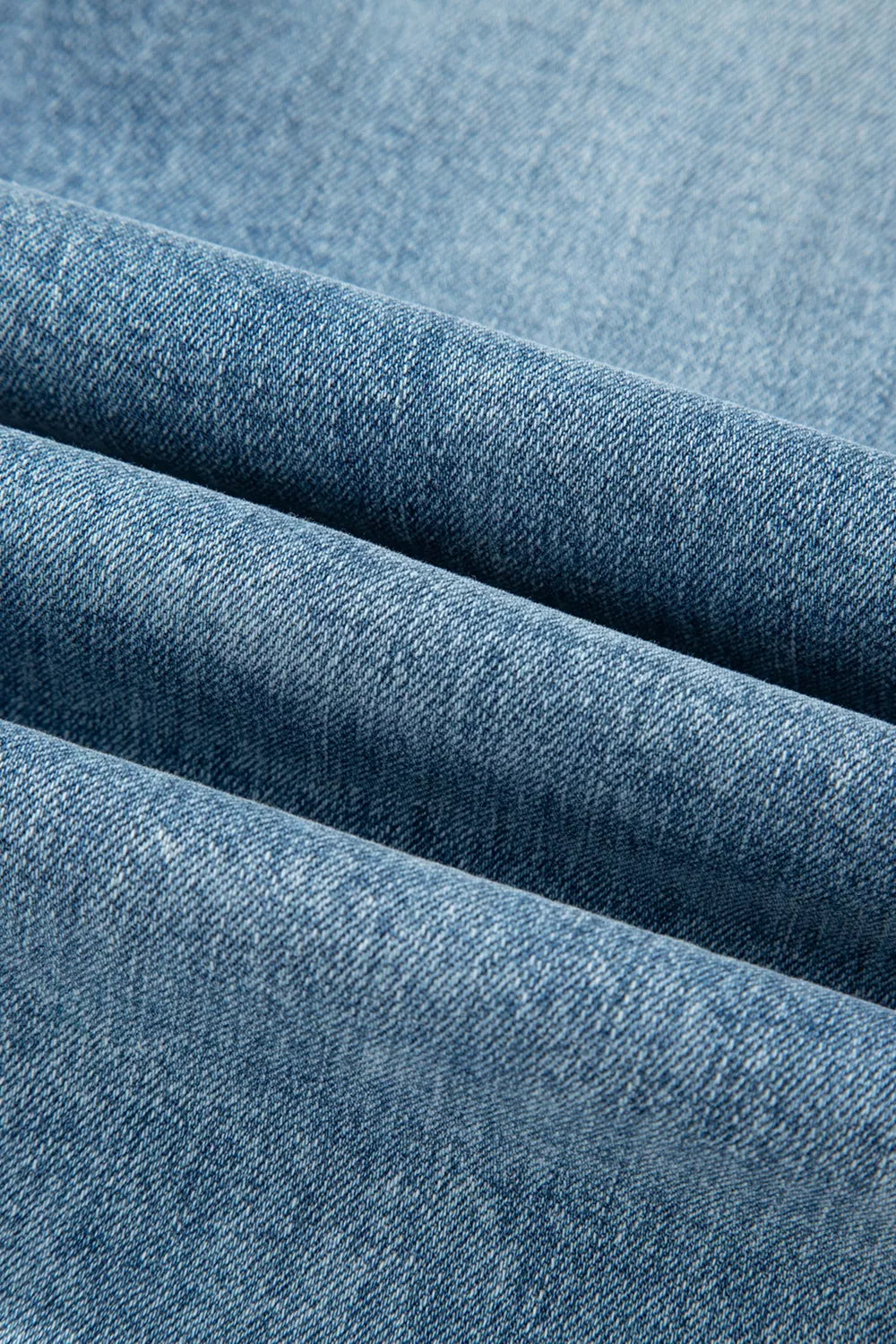 Distressed denim flare jeans in a light blue wash, showing fabric texture.
