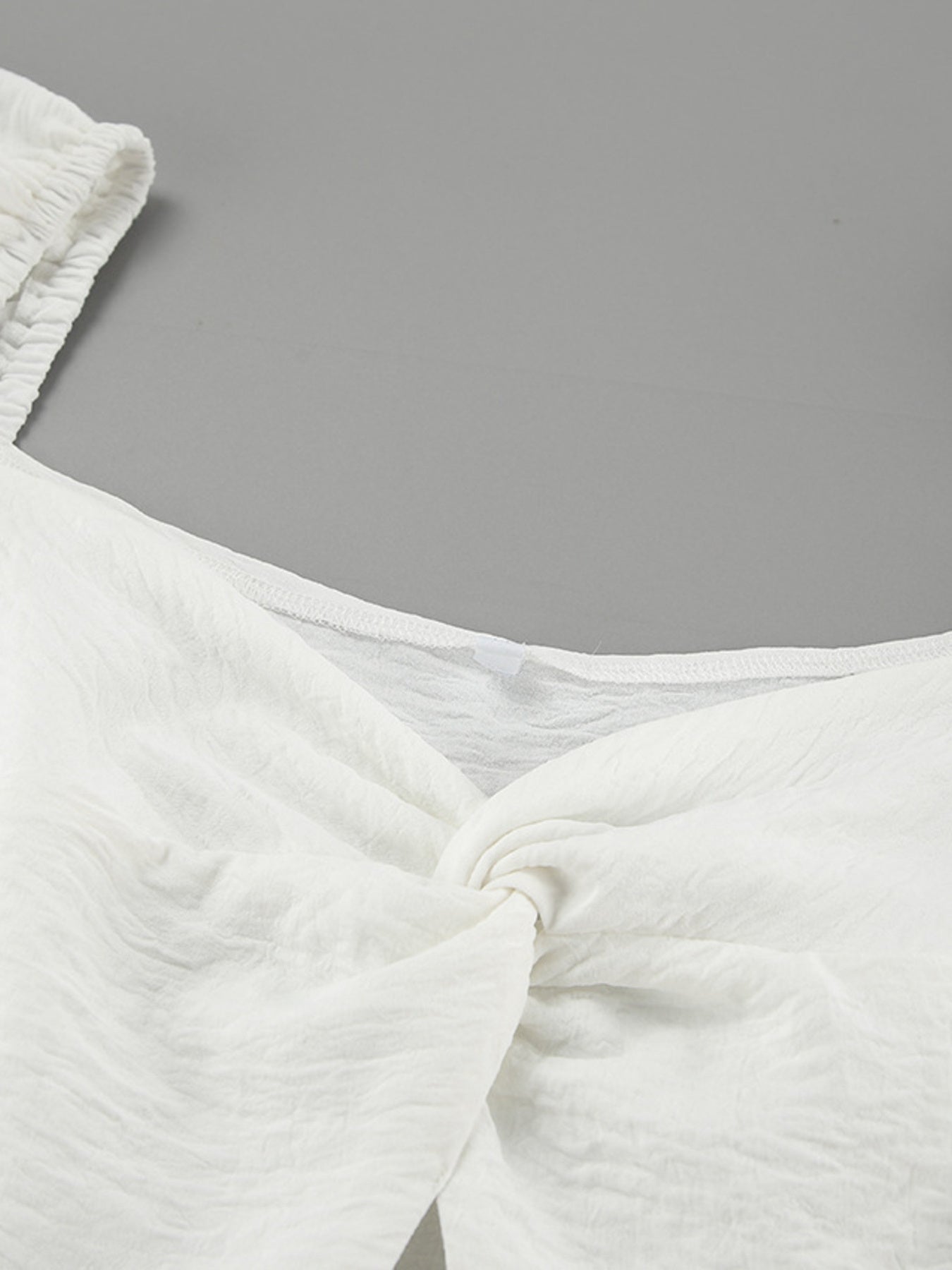 White off-shoulder midi dress with twisted detail and textured fabric