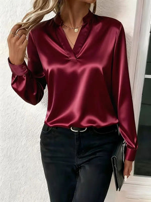 Burgundy satin blouse with notched neckline and long sleeves, styled with black jeans.