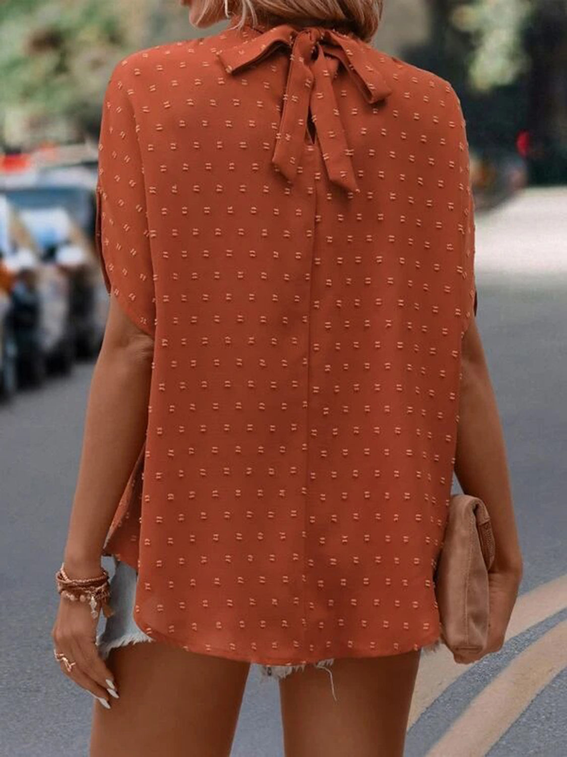 Textured dot back-tie blouse in caramel with short sleeves and a bow detail at the neck.